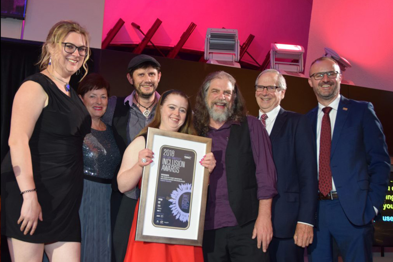 A group of people smile at the camera with an award