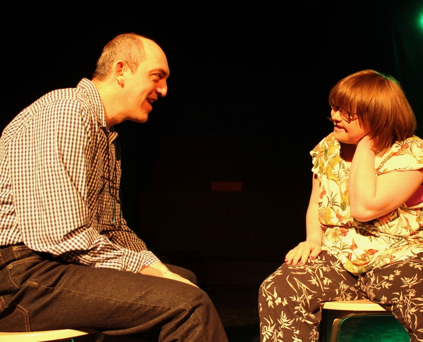 2 people sitting on chairs on a stage