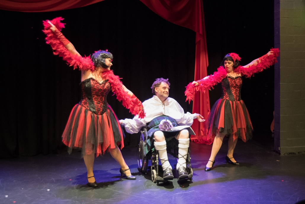 2 women and a man in a wheelchair on stage