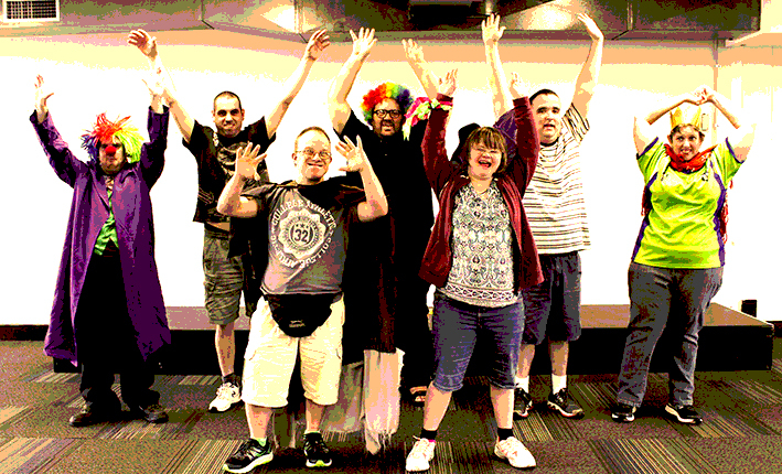 A group of people in clown costumes cheers and raise their hands
