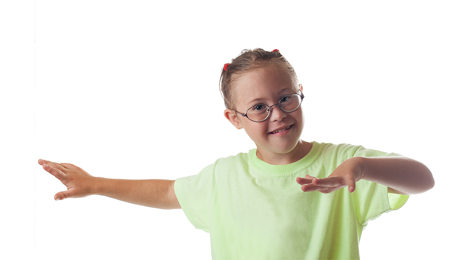 A young girl in a green tshirt smiles while making a dramatic pose