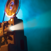 An old film projector shoots out a ray of light with a blue smokey background.