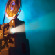 An old film projector shoots out a ray of light with a blue smokey background.