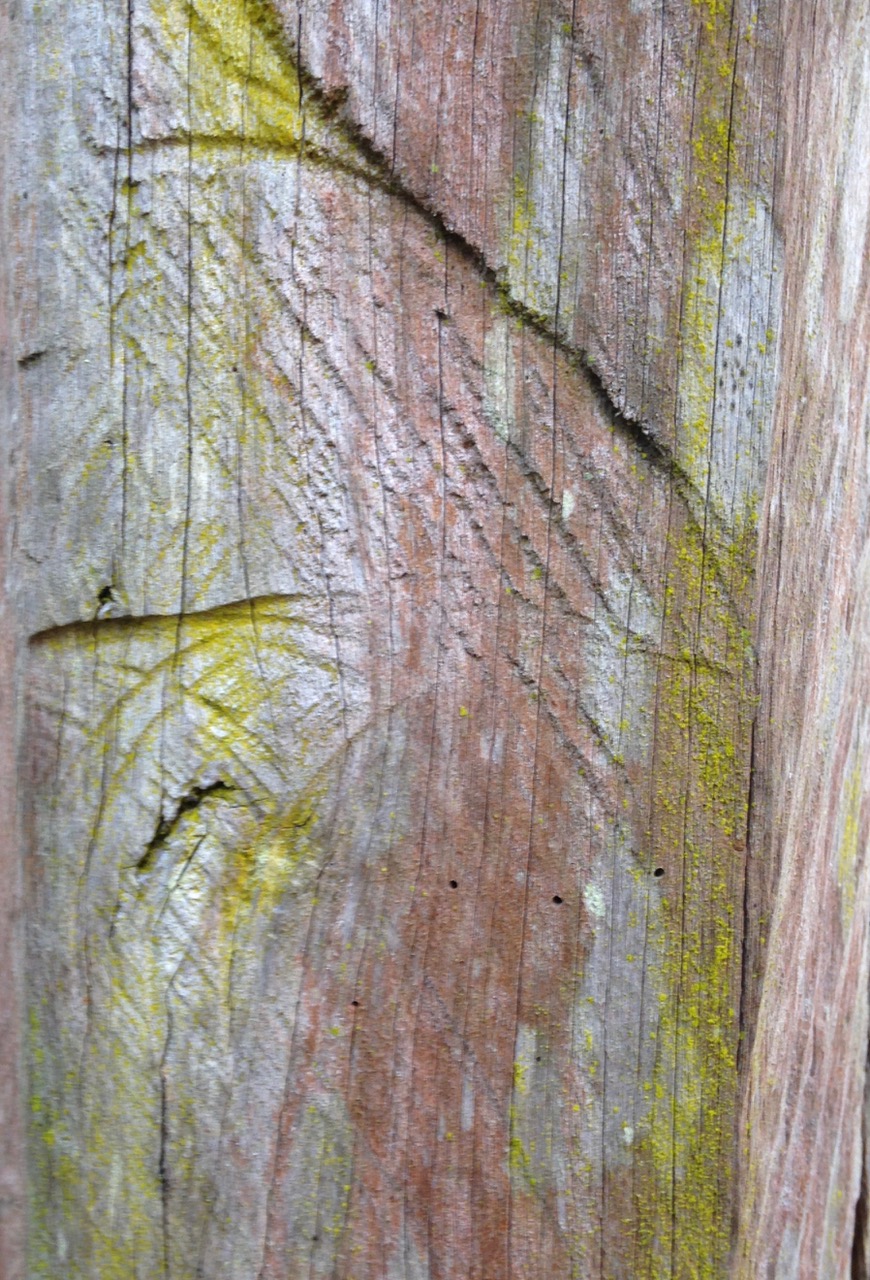 Patterns painted in red brown and yellow on a grey piece of wood