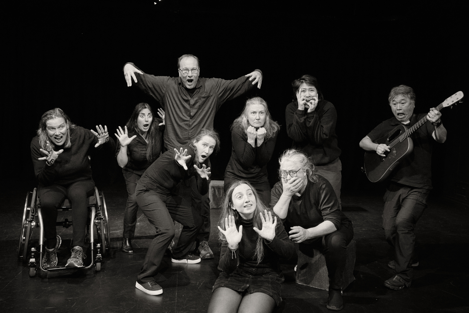 A group of people perform on stage with outstretched arms