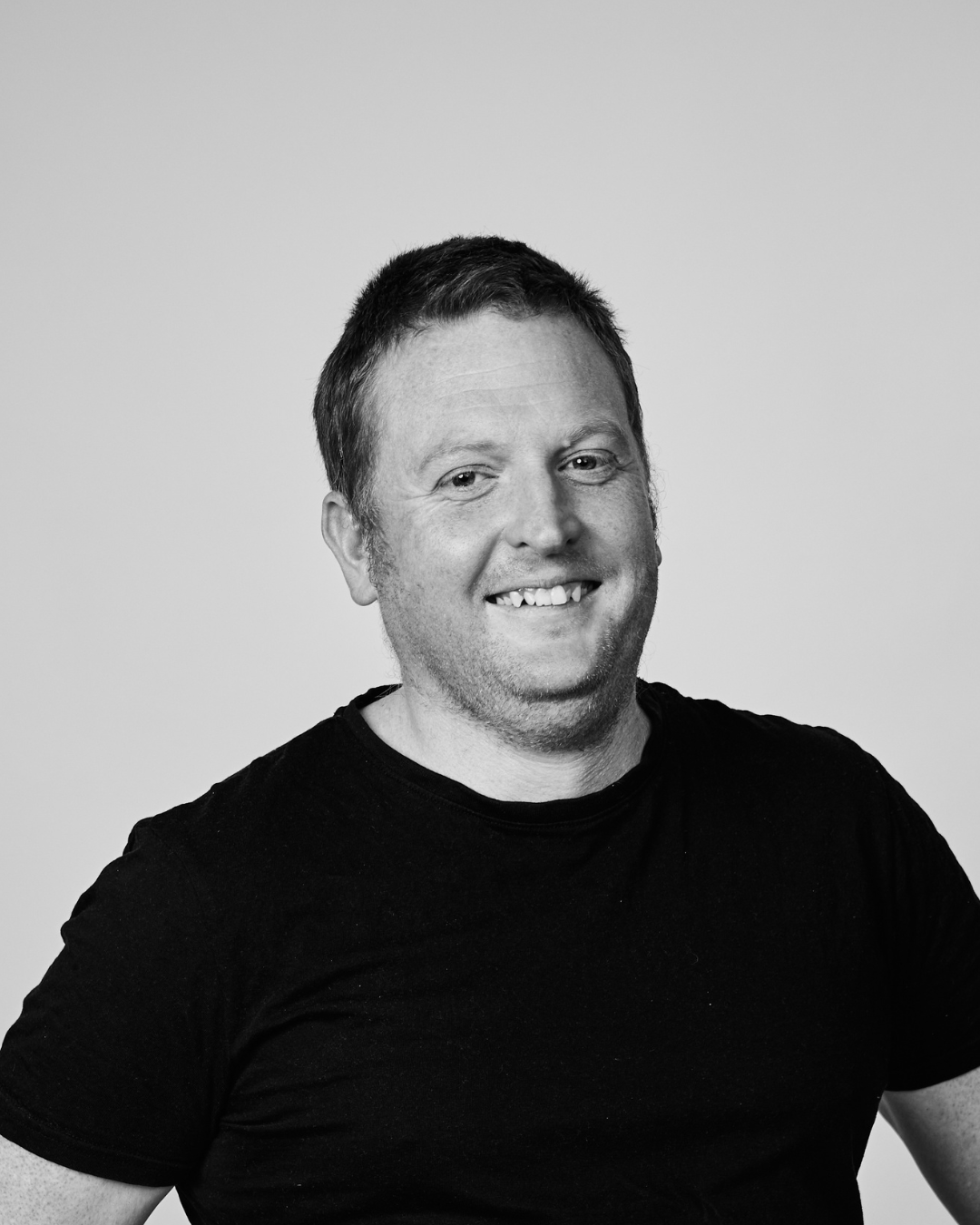 A man in a black shirt smiling at the camera